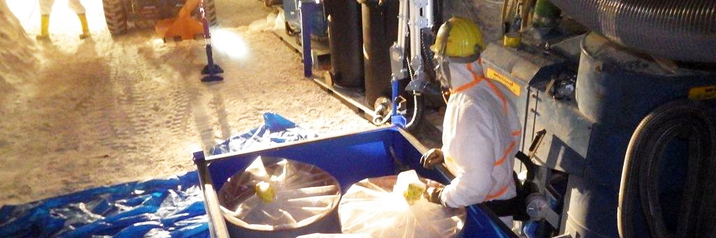 Conditionnement des déchets en caisse de 3 futs sur un chariot manipulé par un homme en tenue de protection